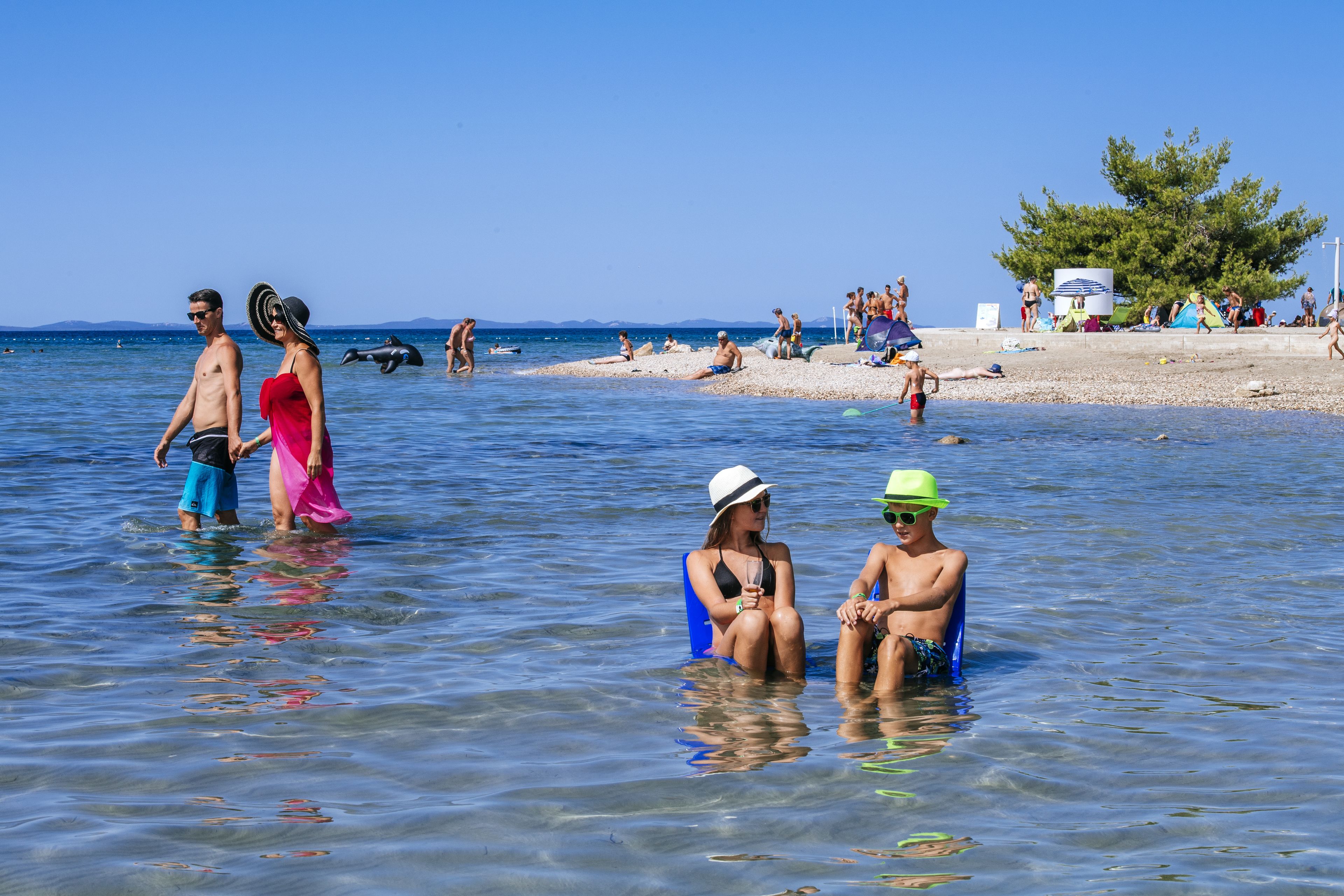 A beach scene with people in the water and on the sand.