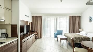 A hotel room with a bed, a desk with a TV, a chair, and a coffee maker.