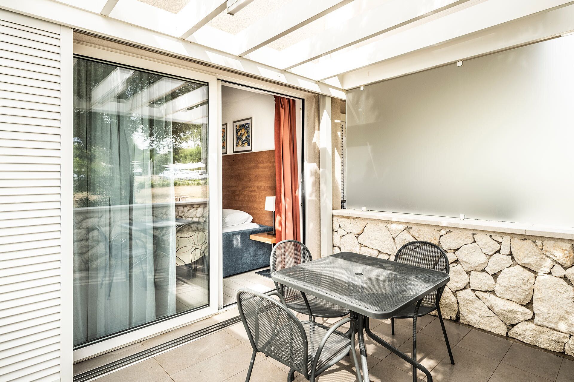 A patio area with a table and chairs, a sliding glass door, and a stone wall.