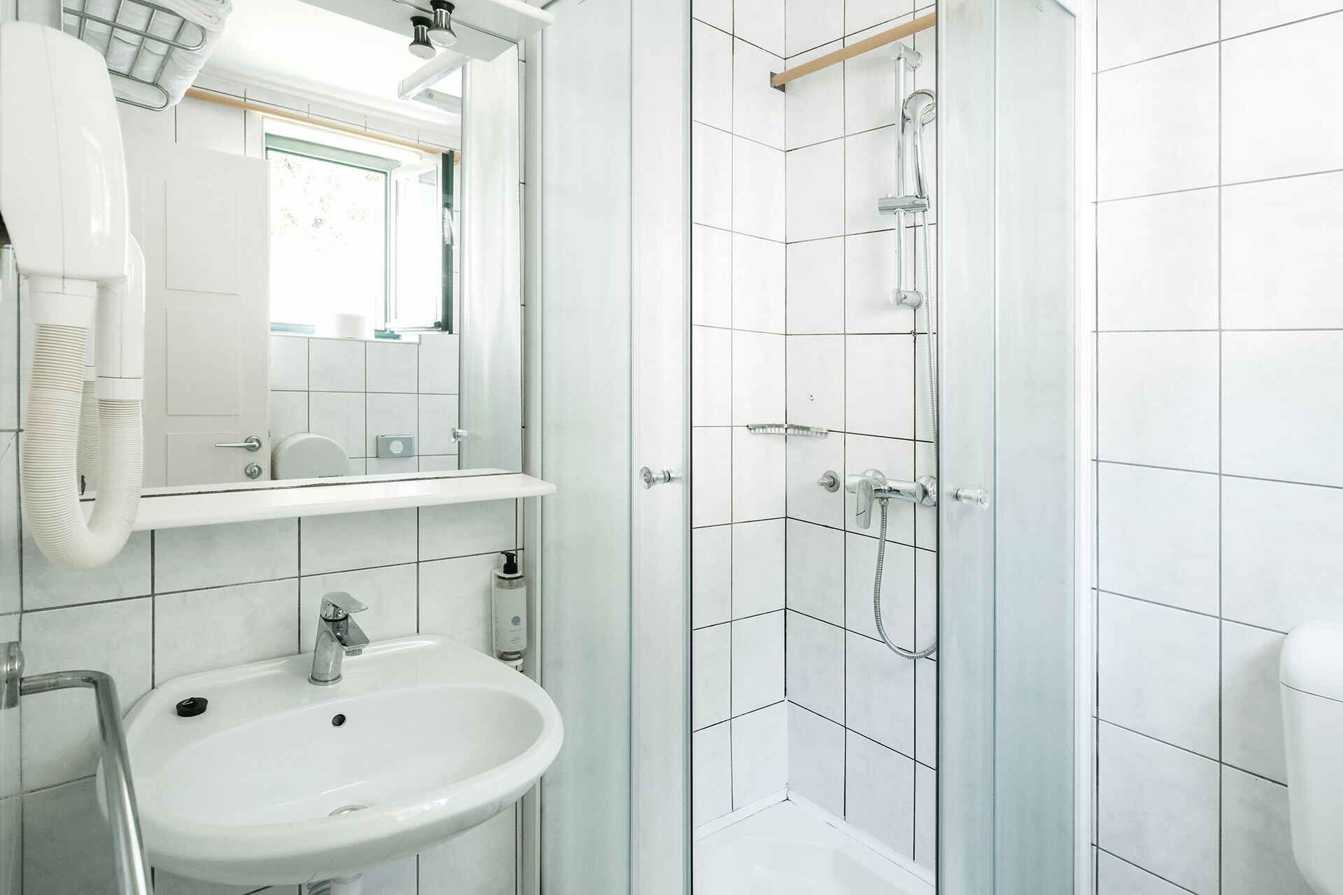 A modern bathroom with a sink, mirror, and shower.