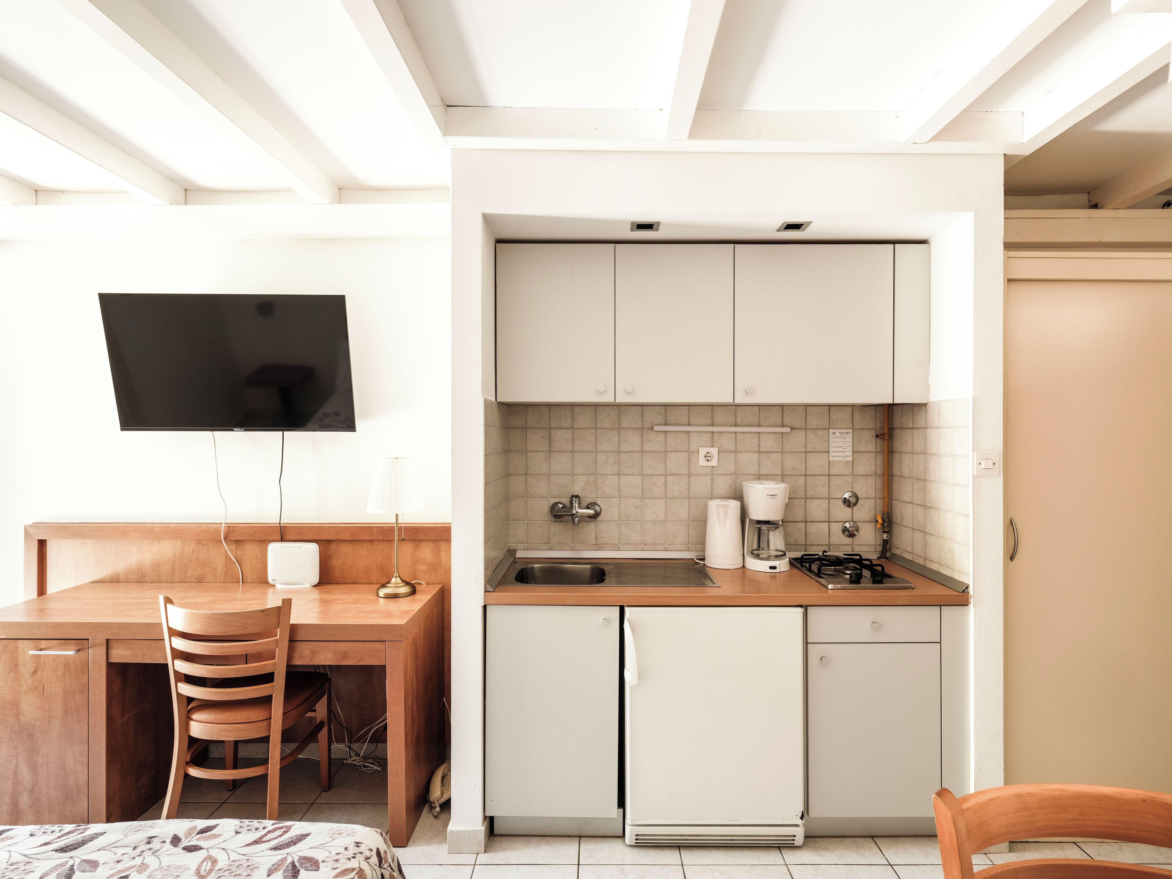 A compact kitchen with a built-in stove, a sink, and a coffee maker.