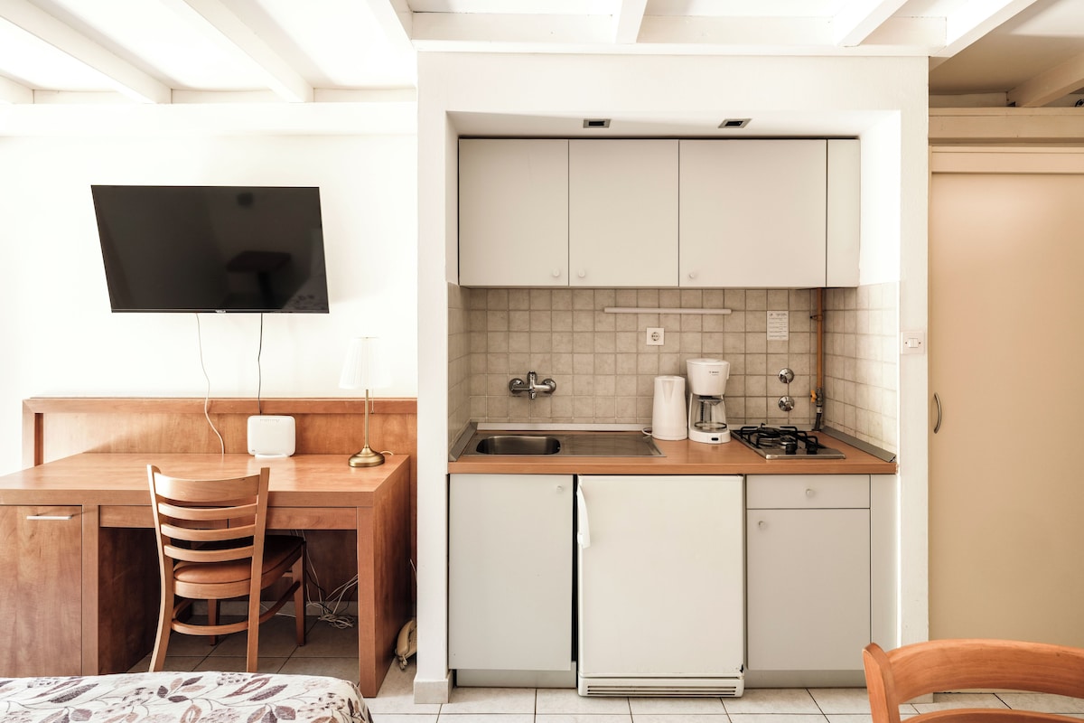 A compact kitchen with a built-in stove, a sink, and a coffee maker.