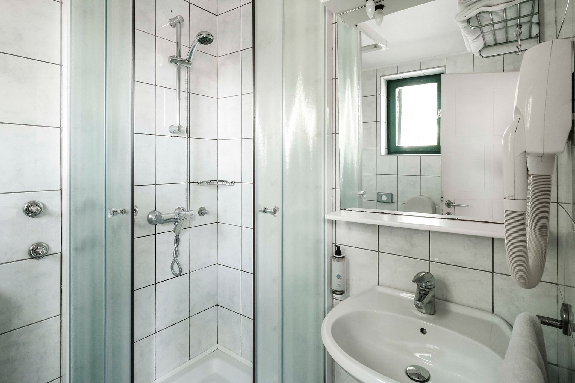 Ein modernes Badezimmer mit einer Duschkabine, einem Waschbecken und einem Spiegel.