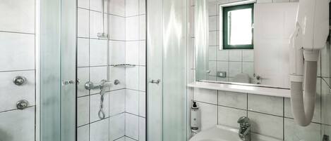 Un baño moderno con ducha envuelta en vidrio, un lavabo y un espejo.