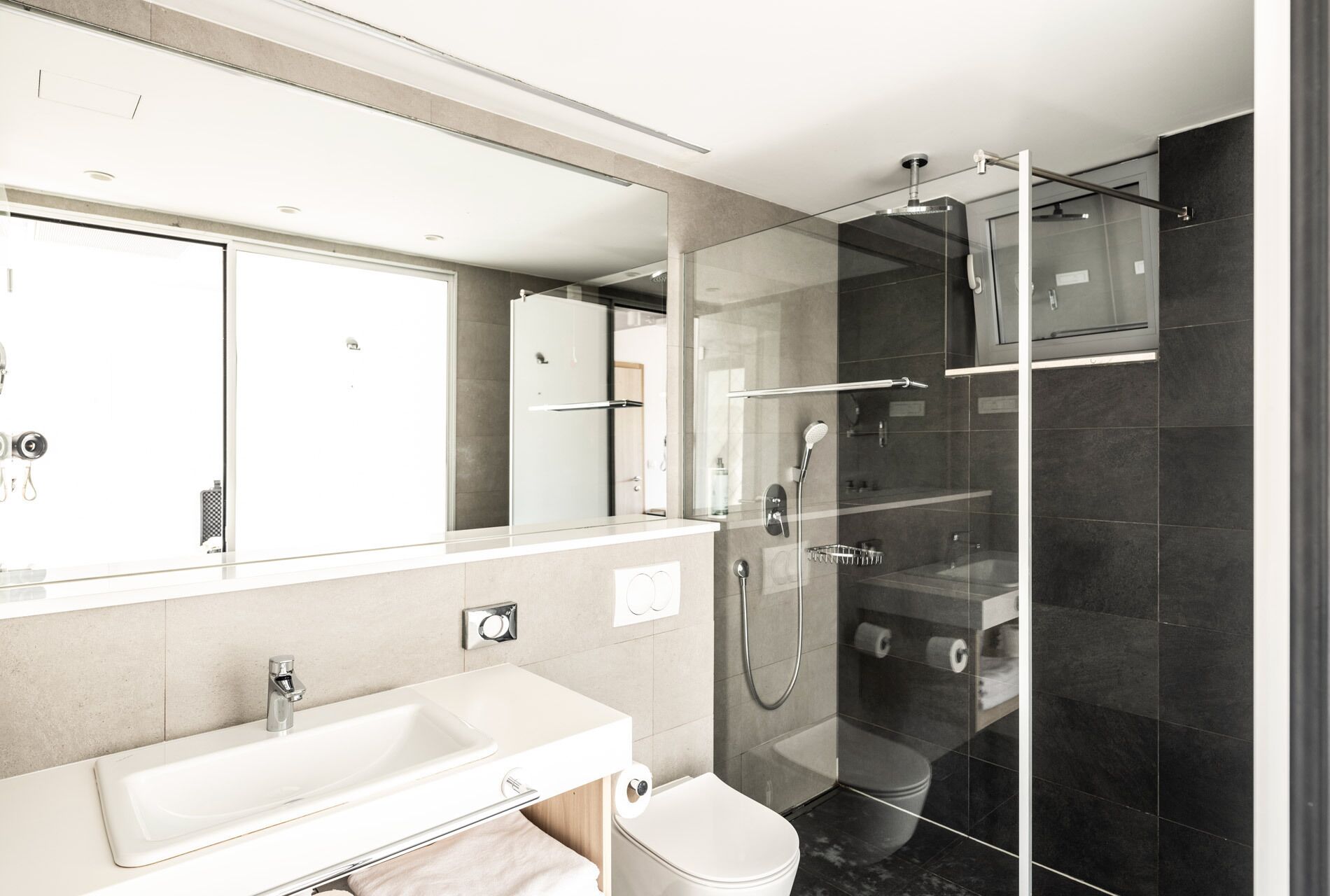 A modern bathroom with a glass-enclosed shower, a white sink, and a large mirror.