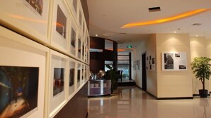 A modern hotel lobby with a polished floor, framed artwork on the walls, a reception desk, and a potted plant. - City Inn Happy Valley Chengdu (Chengdu)