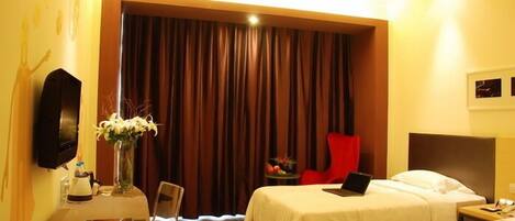 Habitación de hotel con dos camas, un escritorio con una computadora portátil, una silla, un televisor y una cortina.