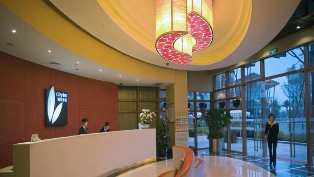 A hotel reception area with a modern design, featuring a reception desk, a large glass window, and a unique spiral chair. - City Inn Happy Valley Chengdu (Chengdu)