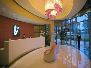 A hotel reception area with a modern design, featuring a reception desk, a large glass window, and a unique spiral chair. - City Inn Happy Valley Chengdu (Chengdu)