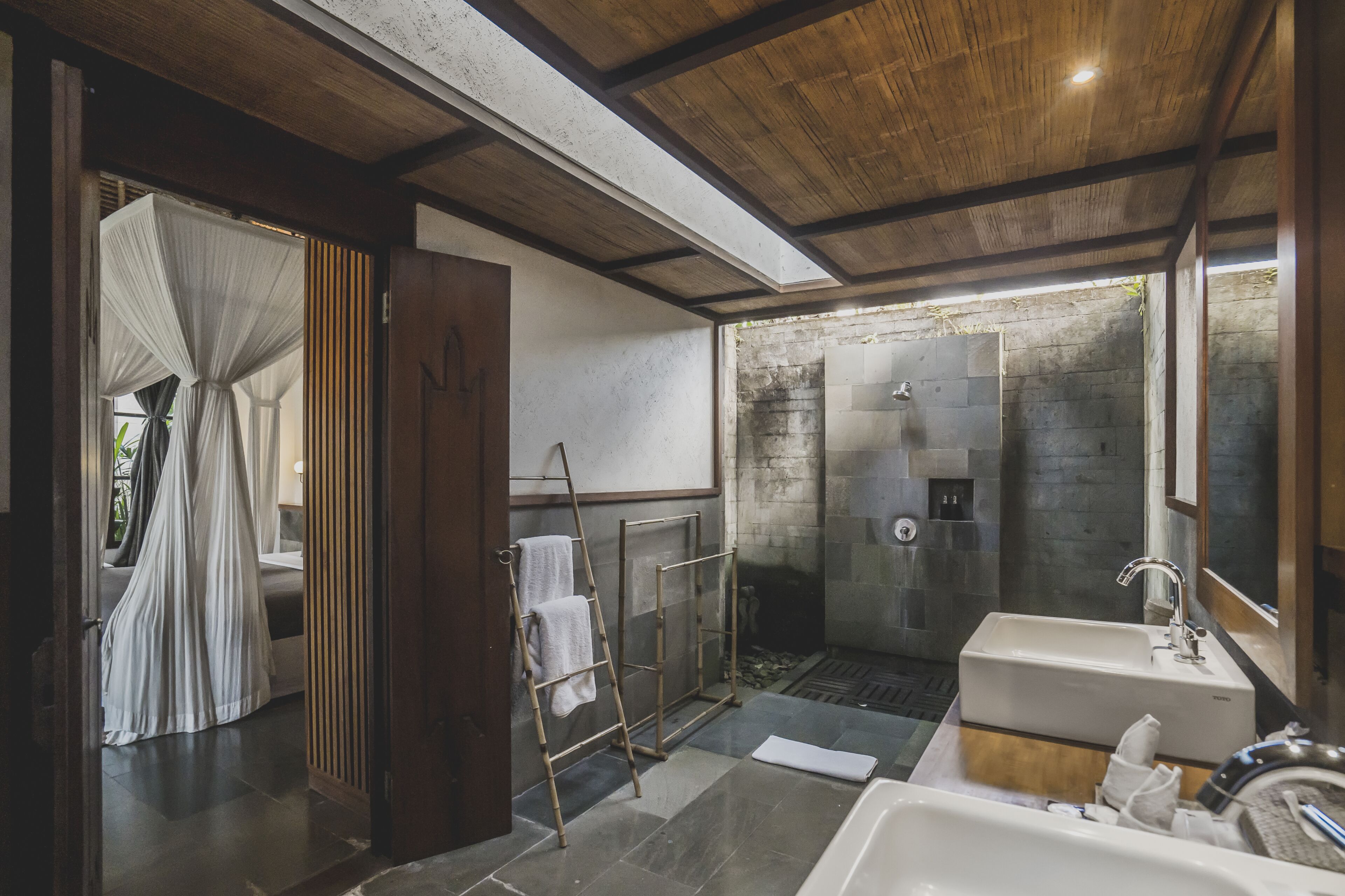 A modern bathroom with a large shower, a bathtub, and a sink. There is a ladder and a towel rack.