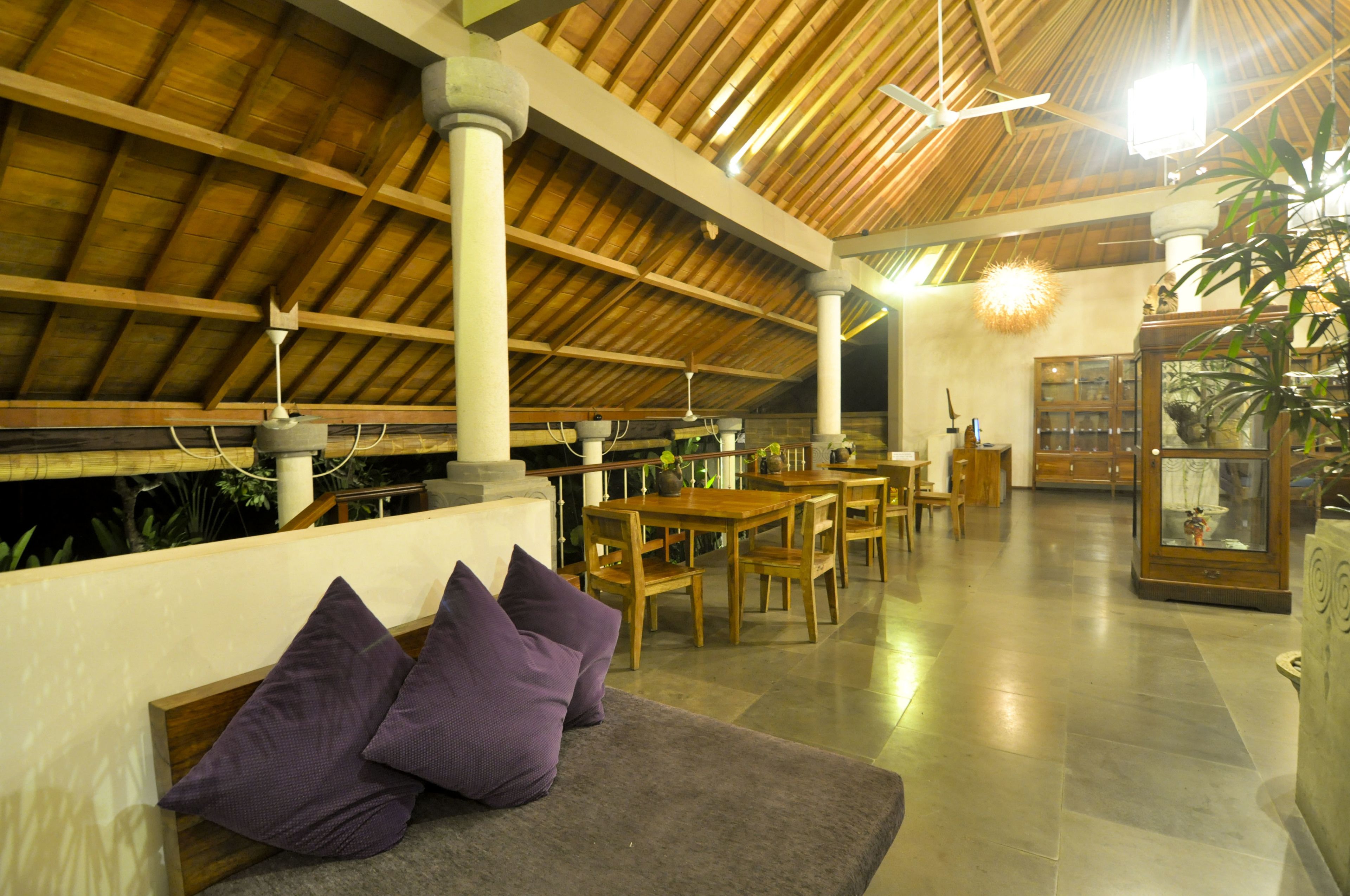 A spacious lobby with wooden ceiling beams, a seating area with purple cushions, and a glass display cabinet.