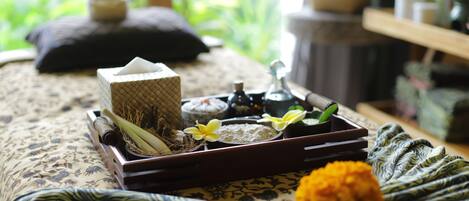 A neatly arranged tray with a tissue box, a small bottle, and a decorative item on a bed with a patterned bedspread.