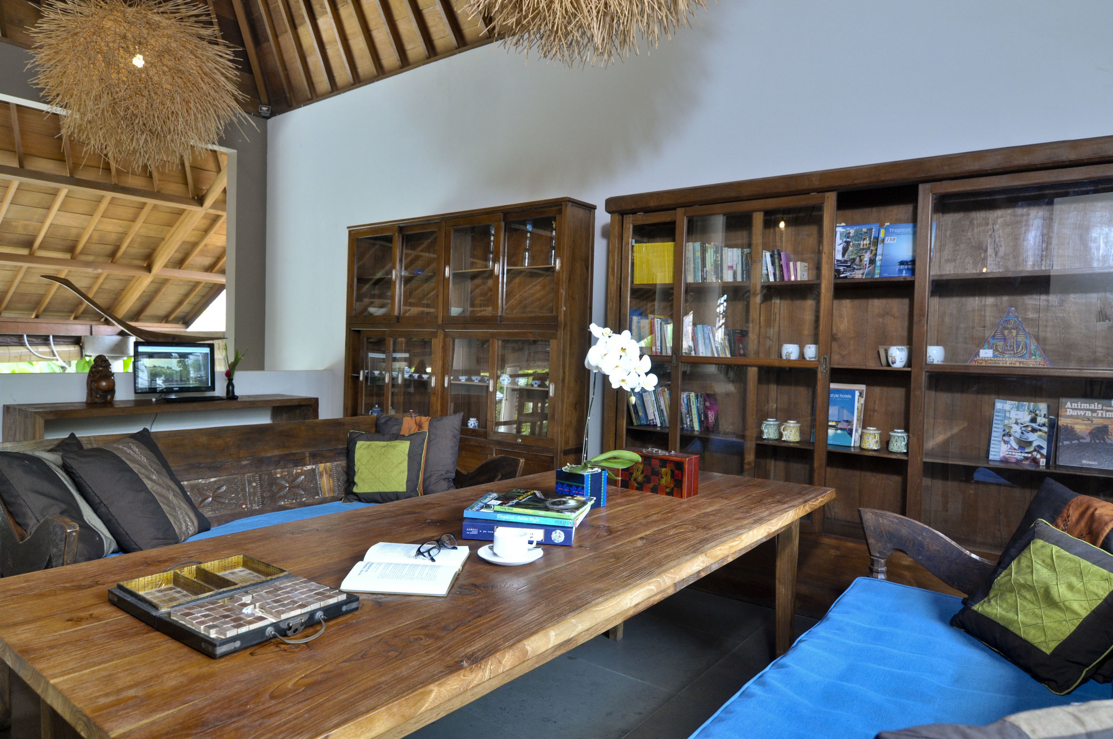 A spacious room with a wooden dining table, bookshelves, and a comfortable seating area.