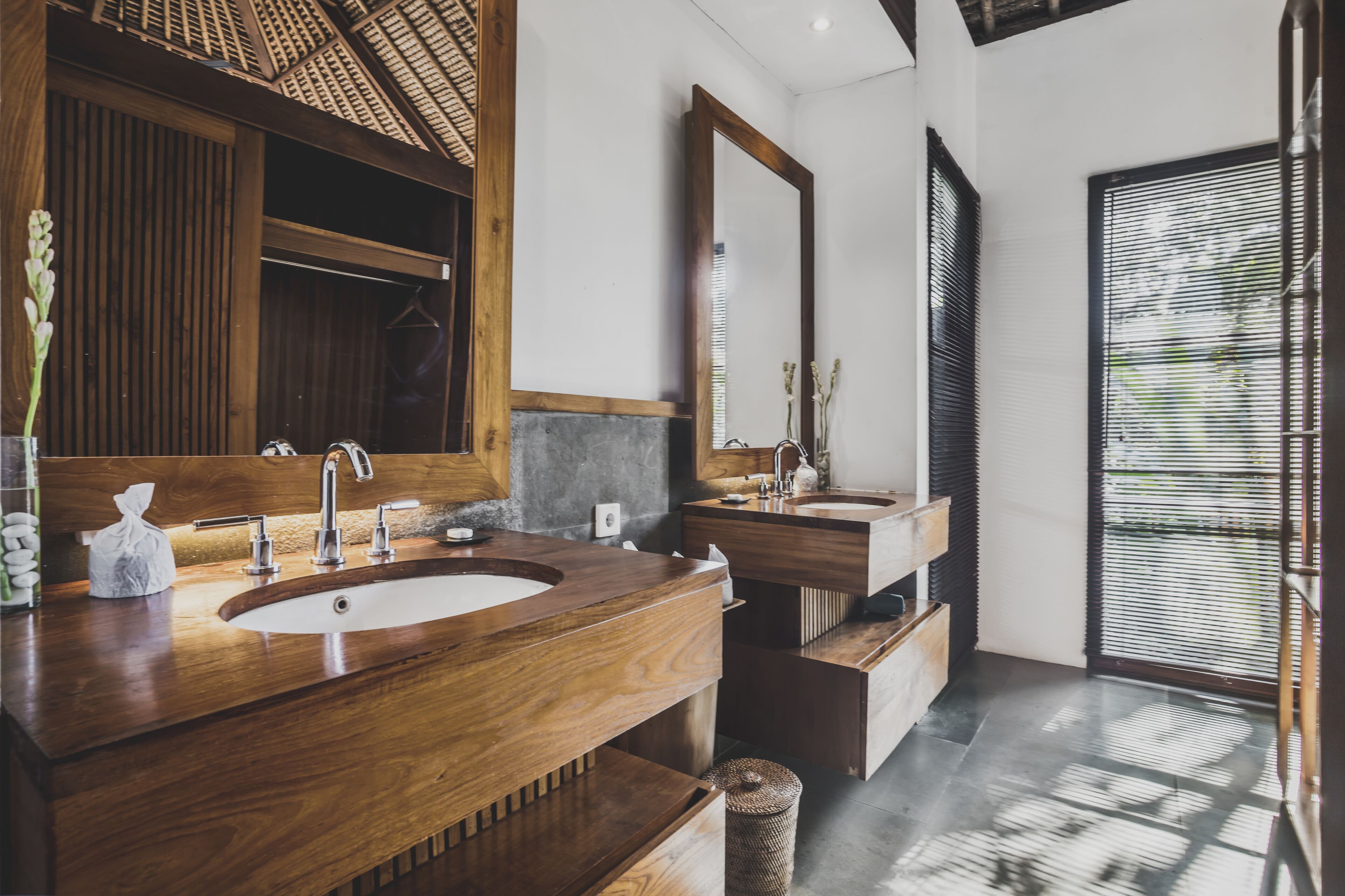 A modern bathroom with a wooden vanity, two sinks, and a large mirror.