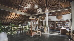 A spacious library with wooden bookshelves, a large reading table, and hanging spherical decorations. - Luwak Ubud Villa & Jungle Suite (Ubud)