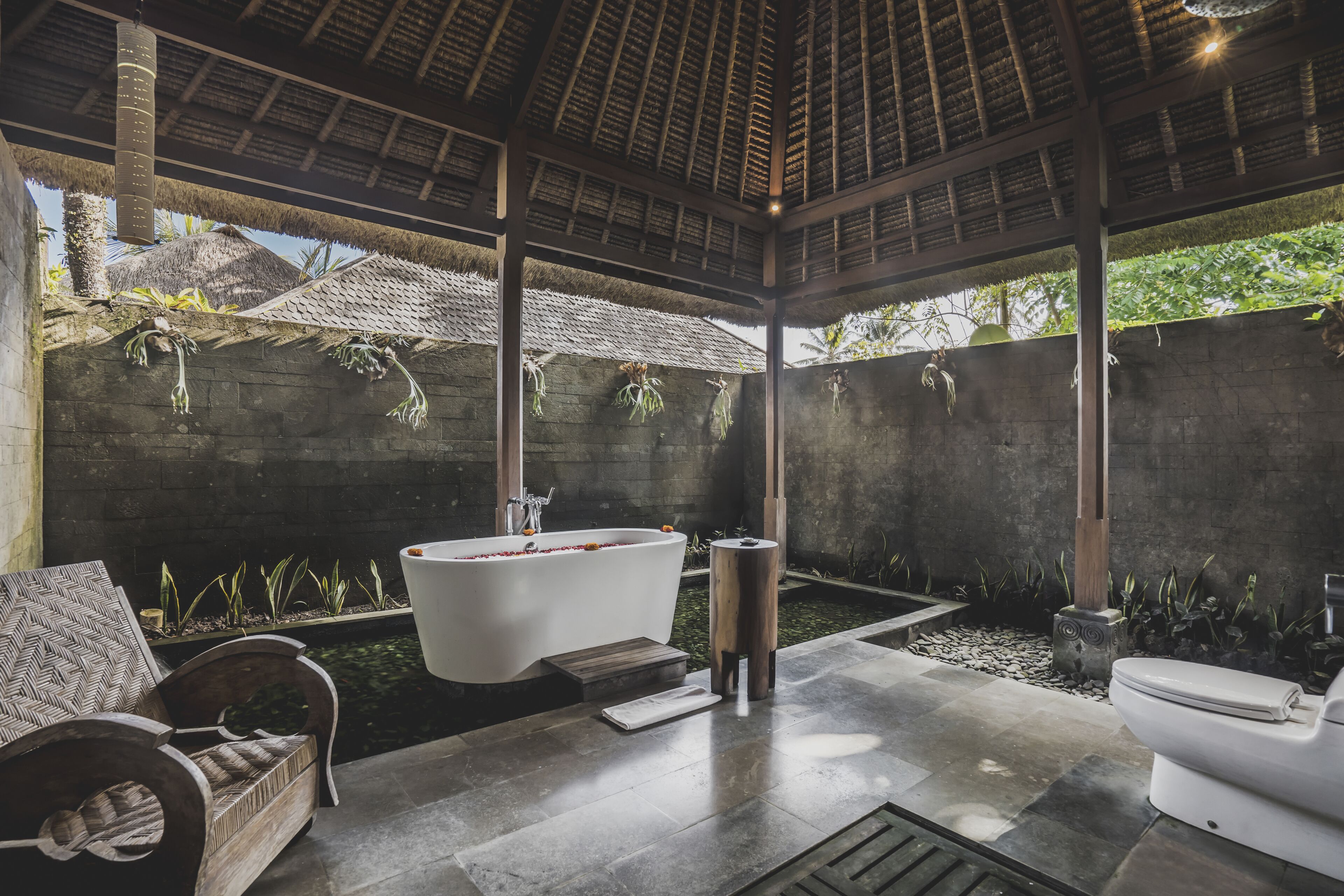 A modern bathroom with a freestanding bathtub, a toilet, and a bench.