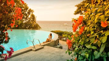 Una piscina al aire libre, una piscina infinita, sombrillas