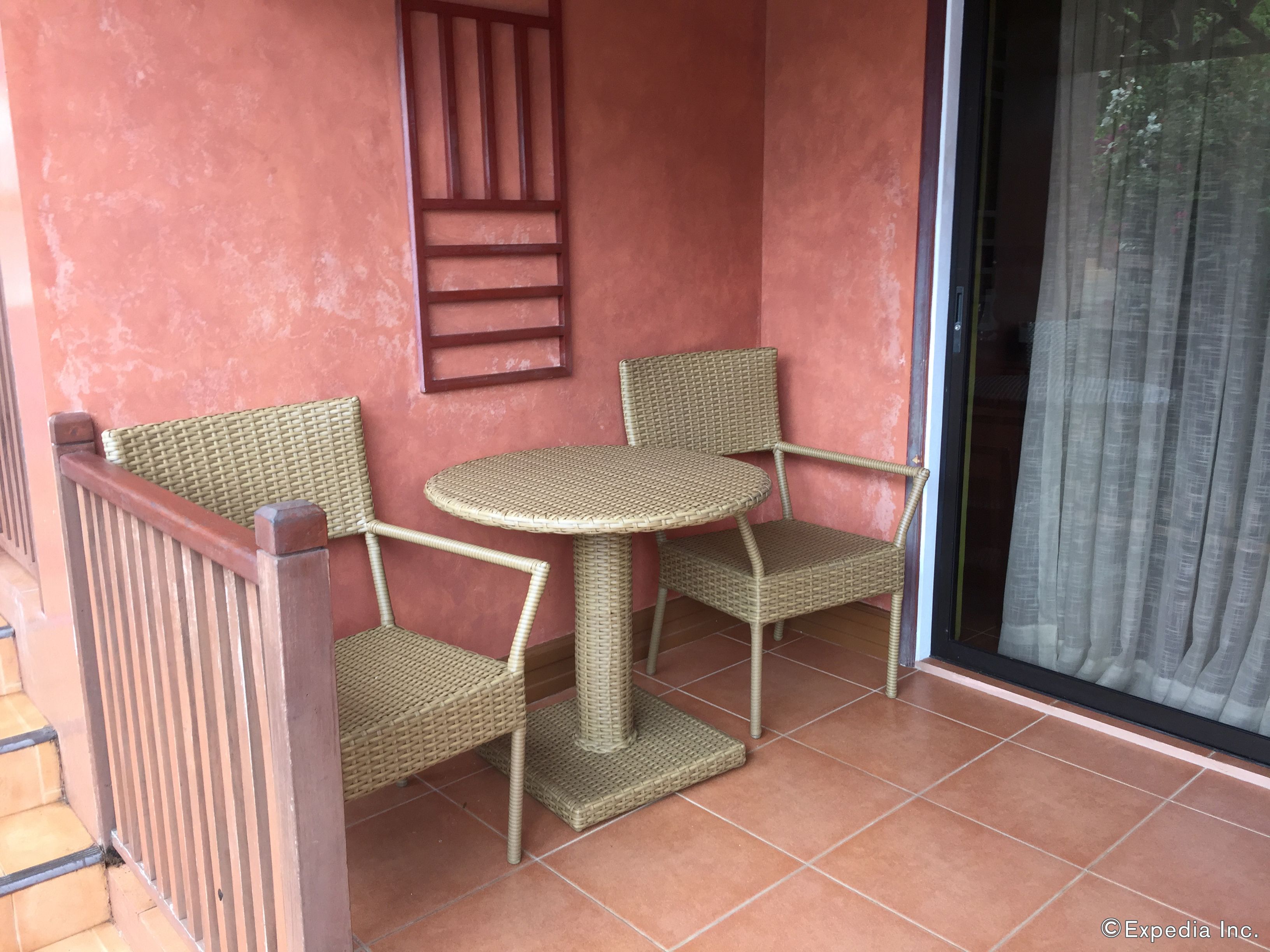 Un petit espace extérieur aménagé avec des meubles en osier et un sol carrelé.