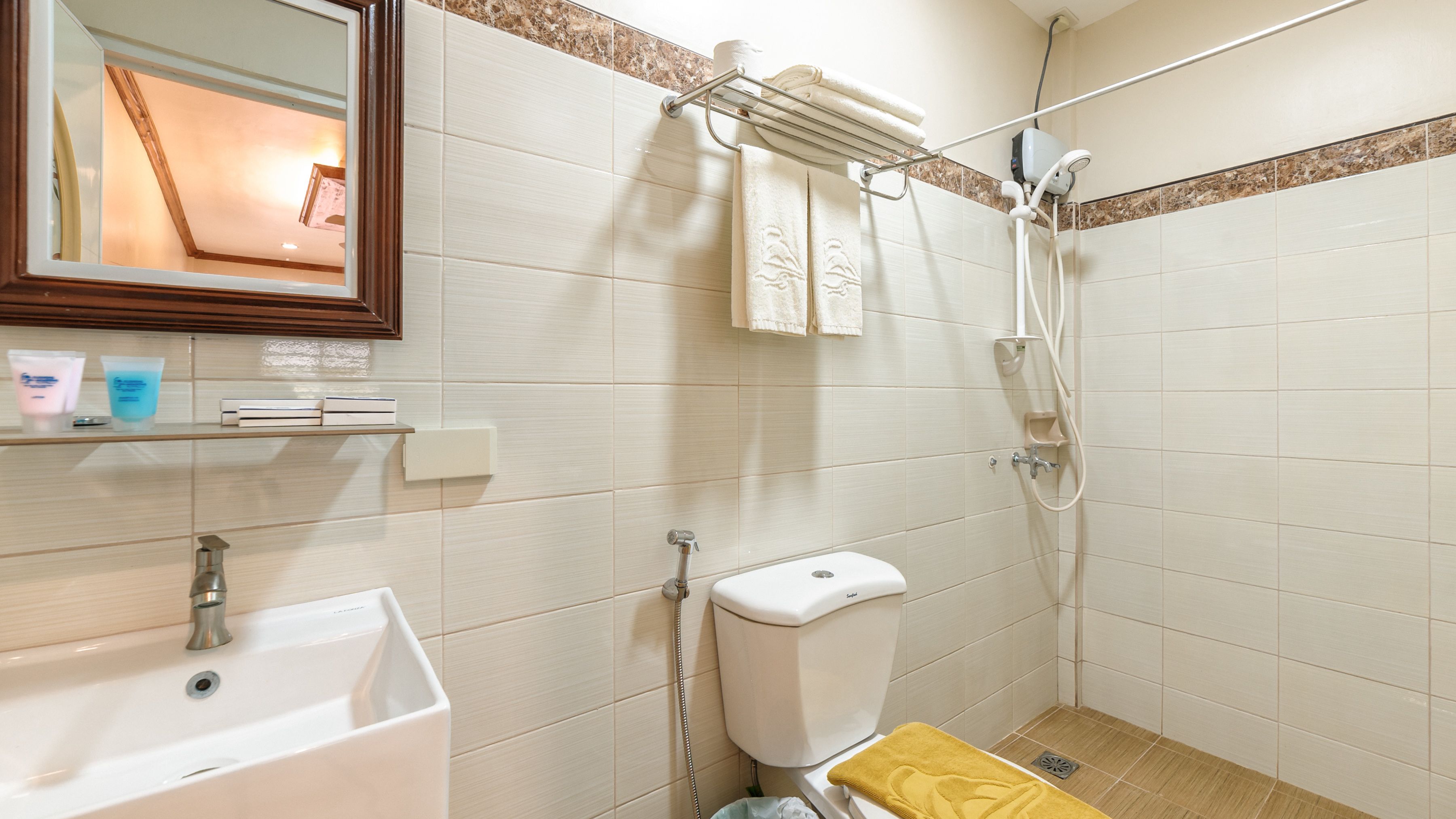 Un baño con lavamanos, inodoro, ducha y espejo.