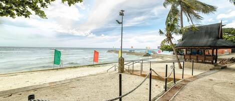 A beach with a wooden structure, a stone pillar, and a rope barrier.