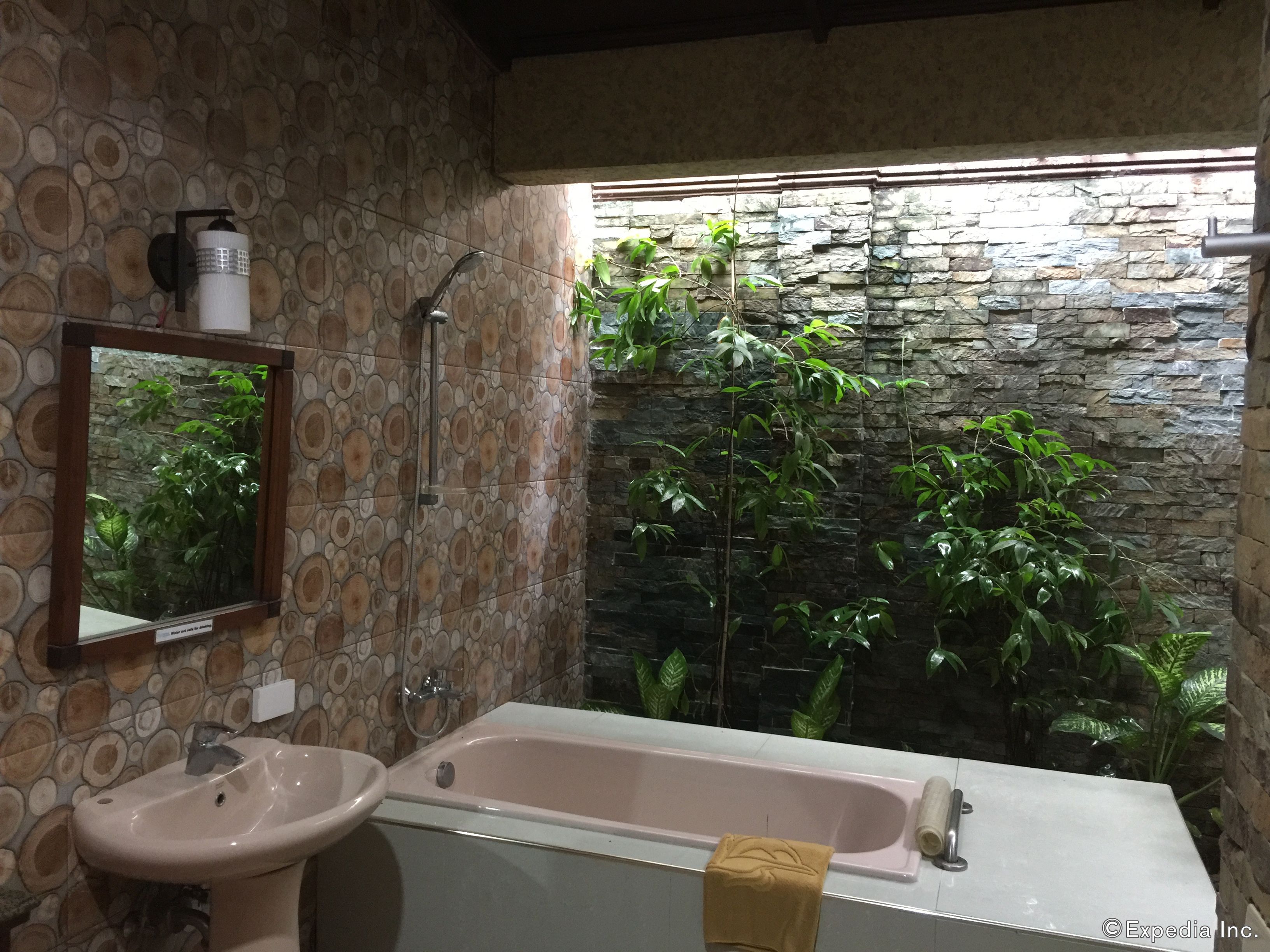 A bathroom with a stone wall, a sink, a bathtub, and a mirror.