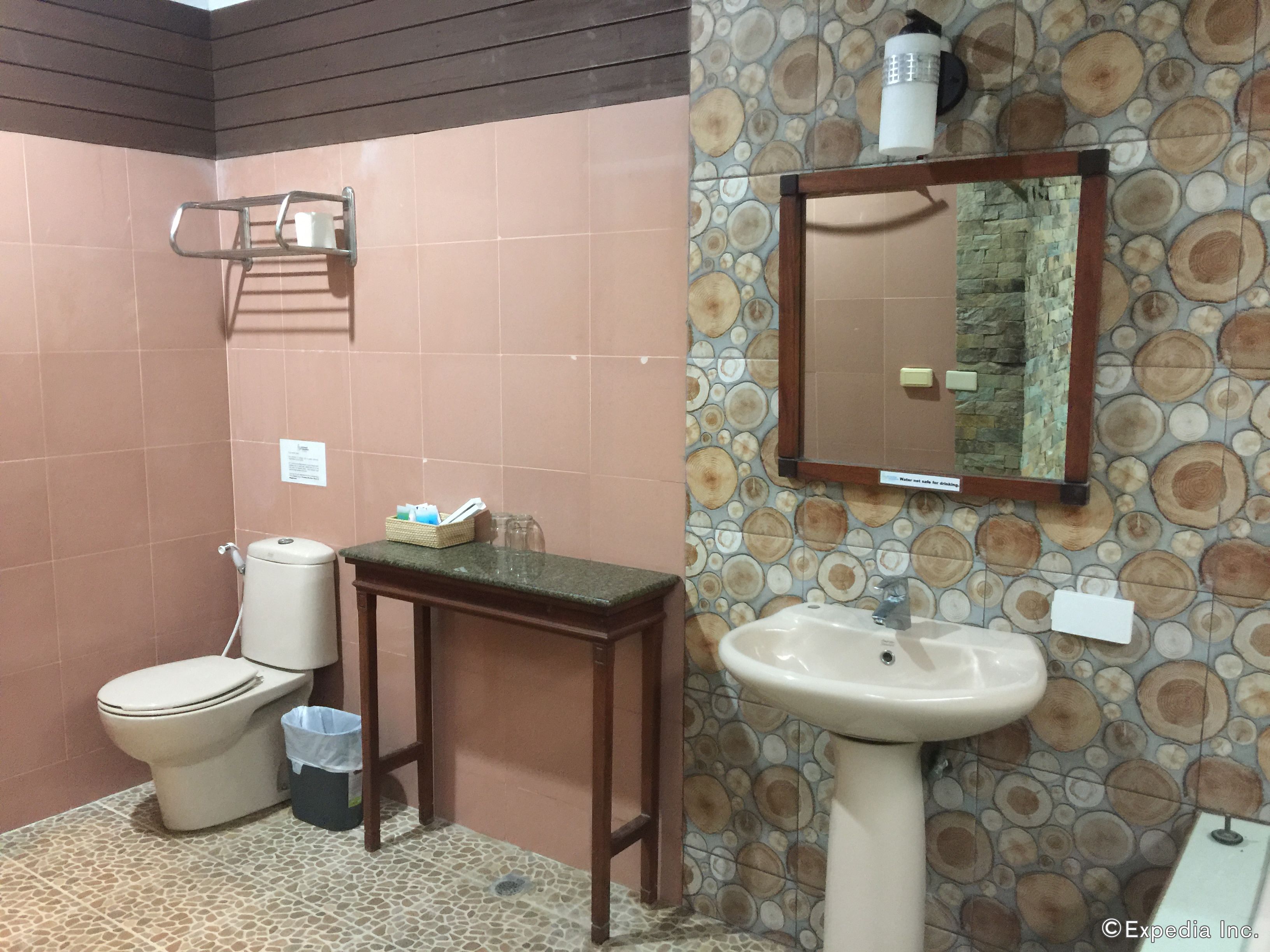 Un baño con inodoro, lavamanos y espejo en la pared.
