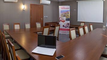 A conference room with a long wooden table, multiple chairs, a laptop, and a smartphone on the table.
