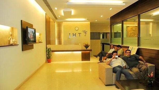 A hotel reception area with a modern design, featuring a reception desk, seating area, and a large window. - Jht Hotels (New Delhi)