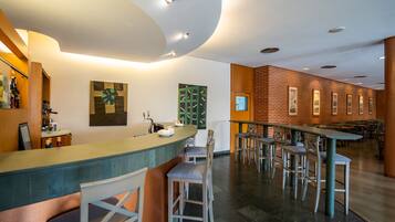 Un área de bar moderna con una barra curva, taburetes y una pared de ladrillo decorativa.