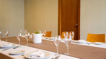 Una mesa de comedor lista para una comida, con platos, cubiertos y copas de vino.