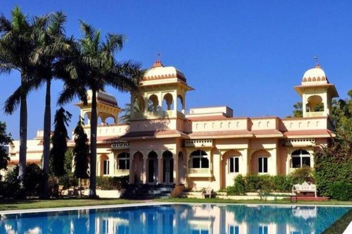 Un edificio grande con piscina, palmeras y cielo azul despejado.
