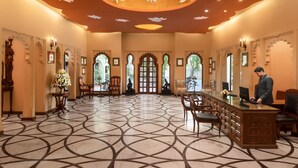 Um hall amplo com piso estampado, arcos ornamentados e um balcão de recepção.
