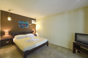 A hotel room with a bed, a painting on the wall, a television, and two bedside lamps.