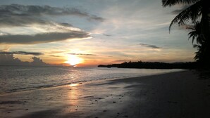 A beach with a sunset, palm trees, and a calm sea. - The Lazy Dog Bed & Breakfast (Boracay Island)