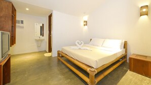 A room with a bed, a television, a sink, and a wall-mounted light fixture. - The Lazy Dog Bed & Breakfast (Boracay Island)