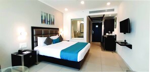 A modern hotel room with a large bed, bedside tables, a flat-screen TV, and a bathroom visible through an open door. - The HQ (Vasco da Gama)