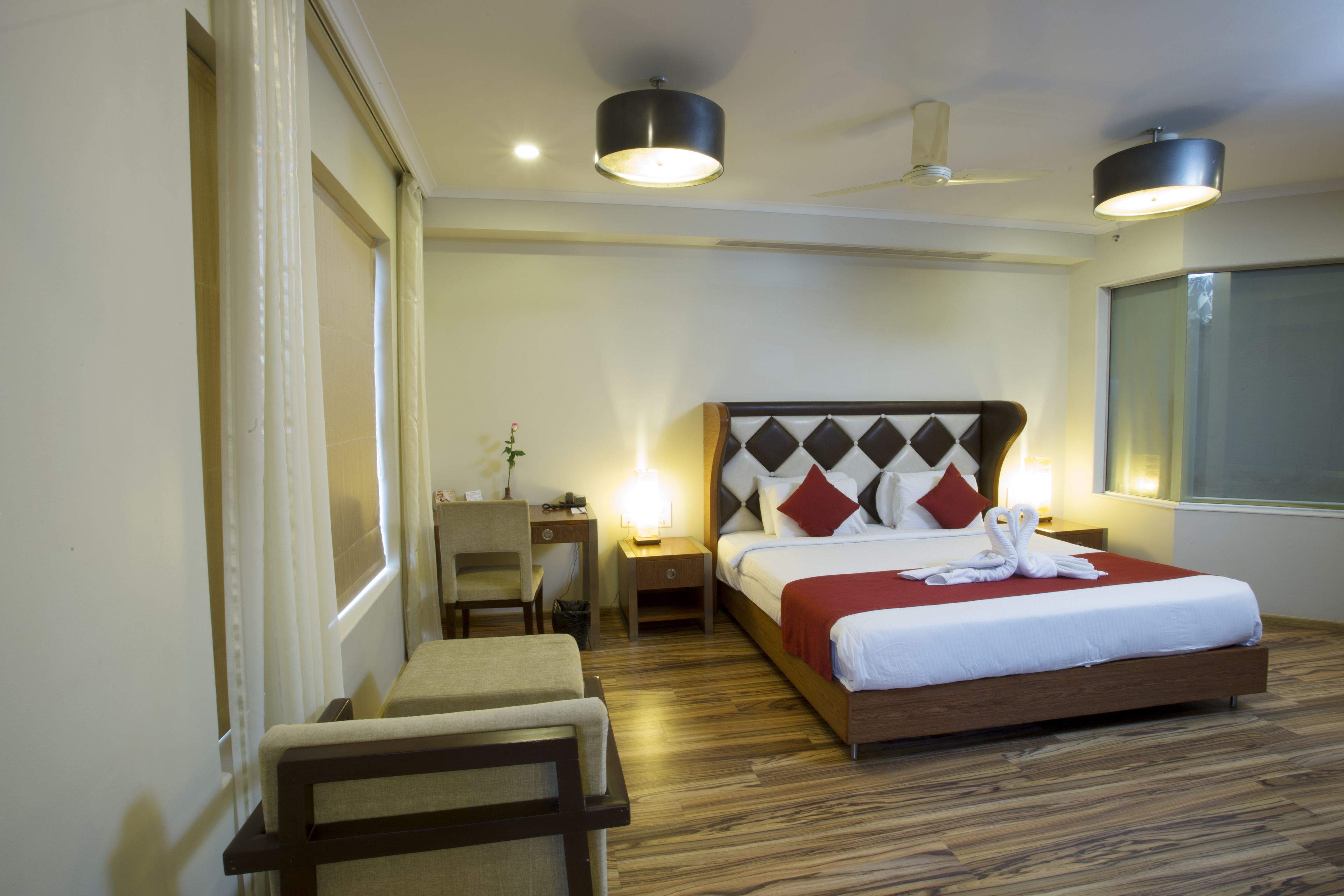 A hotel room with a large bed, bedside tables, a desk, and a chair.