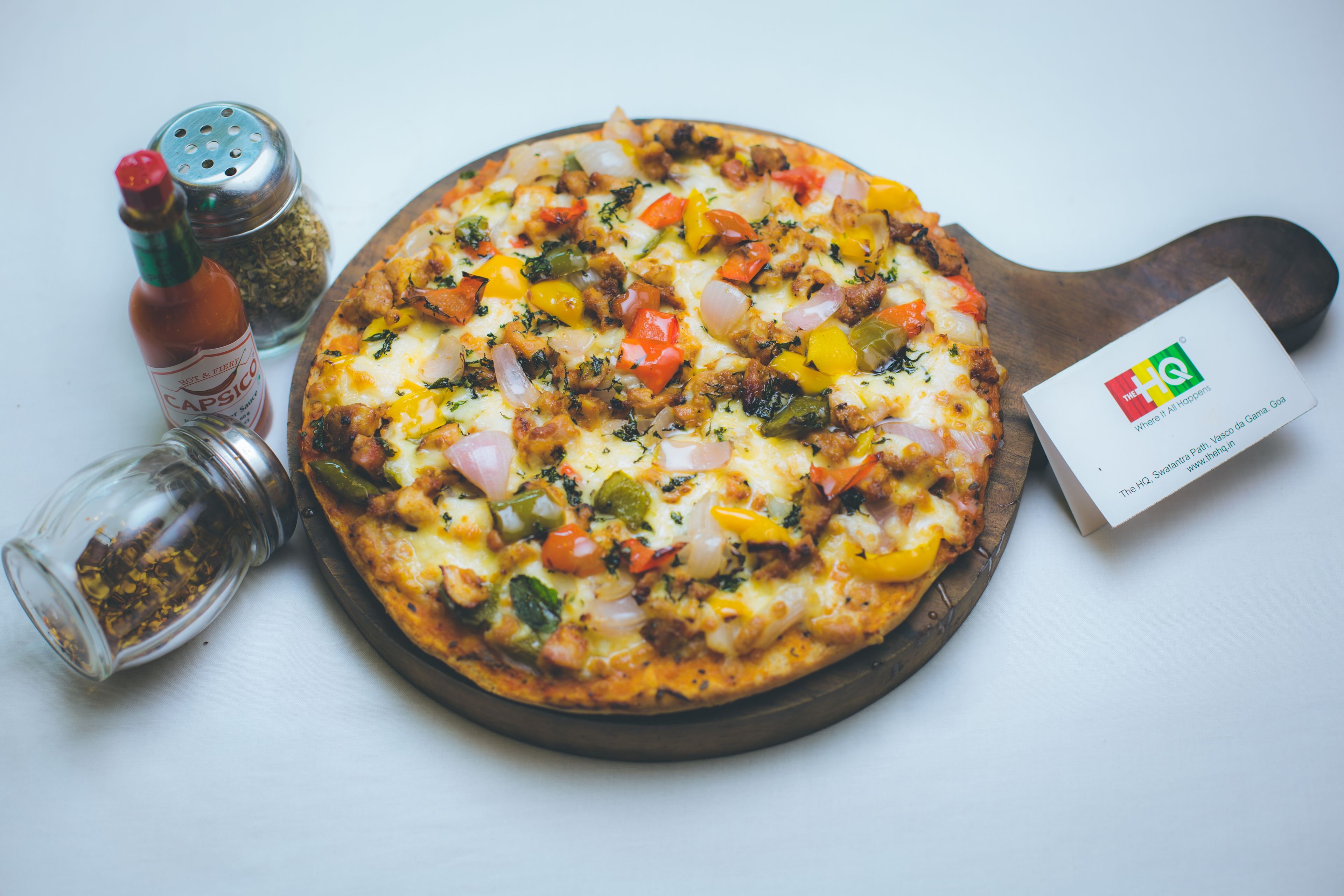 Pizza con diferentes ingredientes, un molinillo de pimienta, un salero y una tarjeta de presentación.