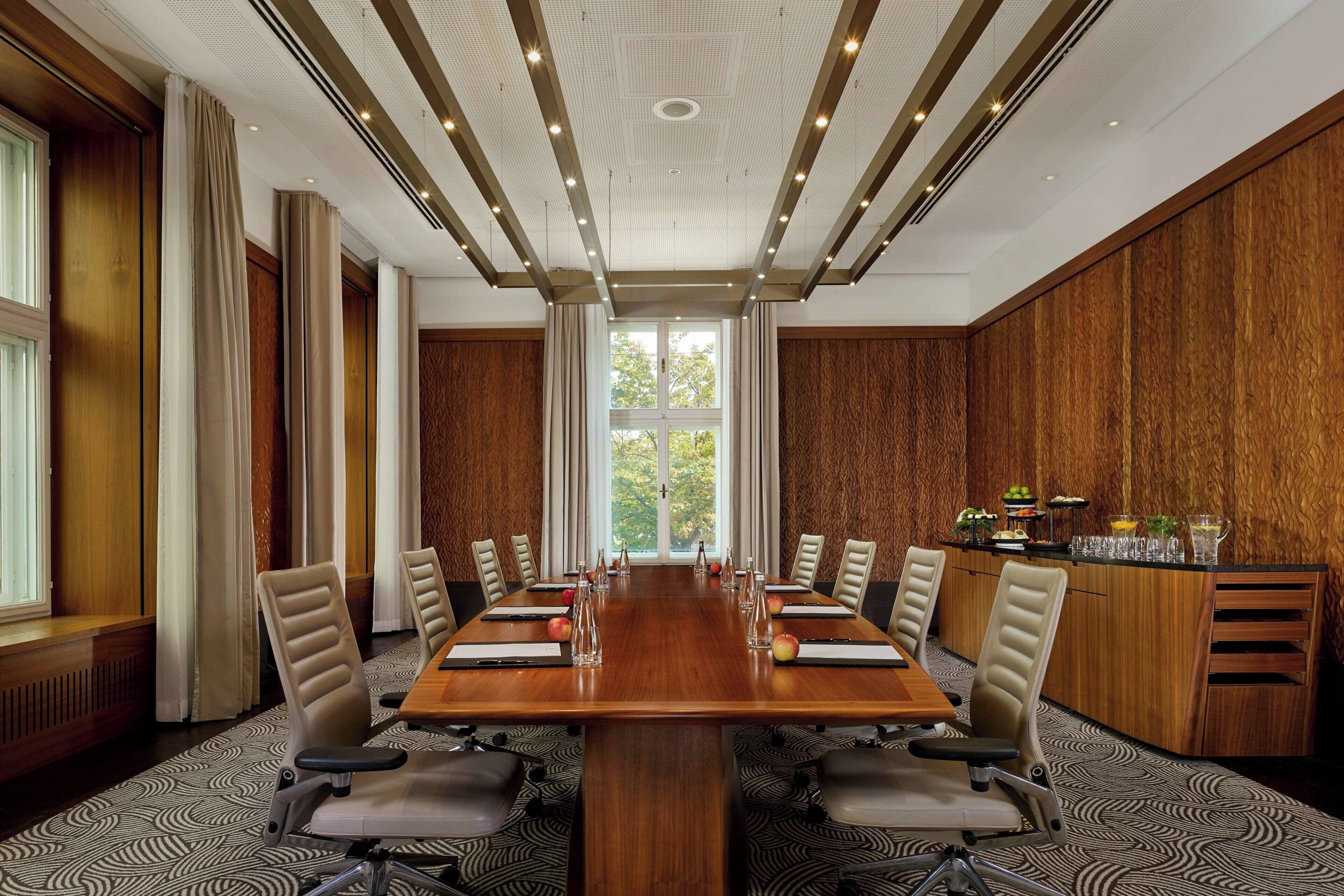 Una sala conferenze con un lungo tavolo, sedie e una parete rivestita in legno.