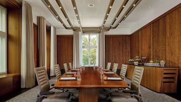 Una sala conferenze con un lungo tavolo, sedie e una parete rivestita in legno.