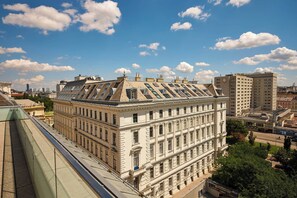 A multi-story building with a classical architectural style, featuring a prominent central section with large windows and a flat roof with skylights.