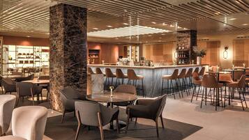 Eine moderne Bar mit Marmorsäulen, Sitzgelegenheiten und freundlicher Beleuchtung.