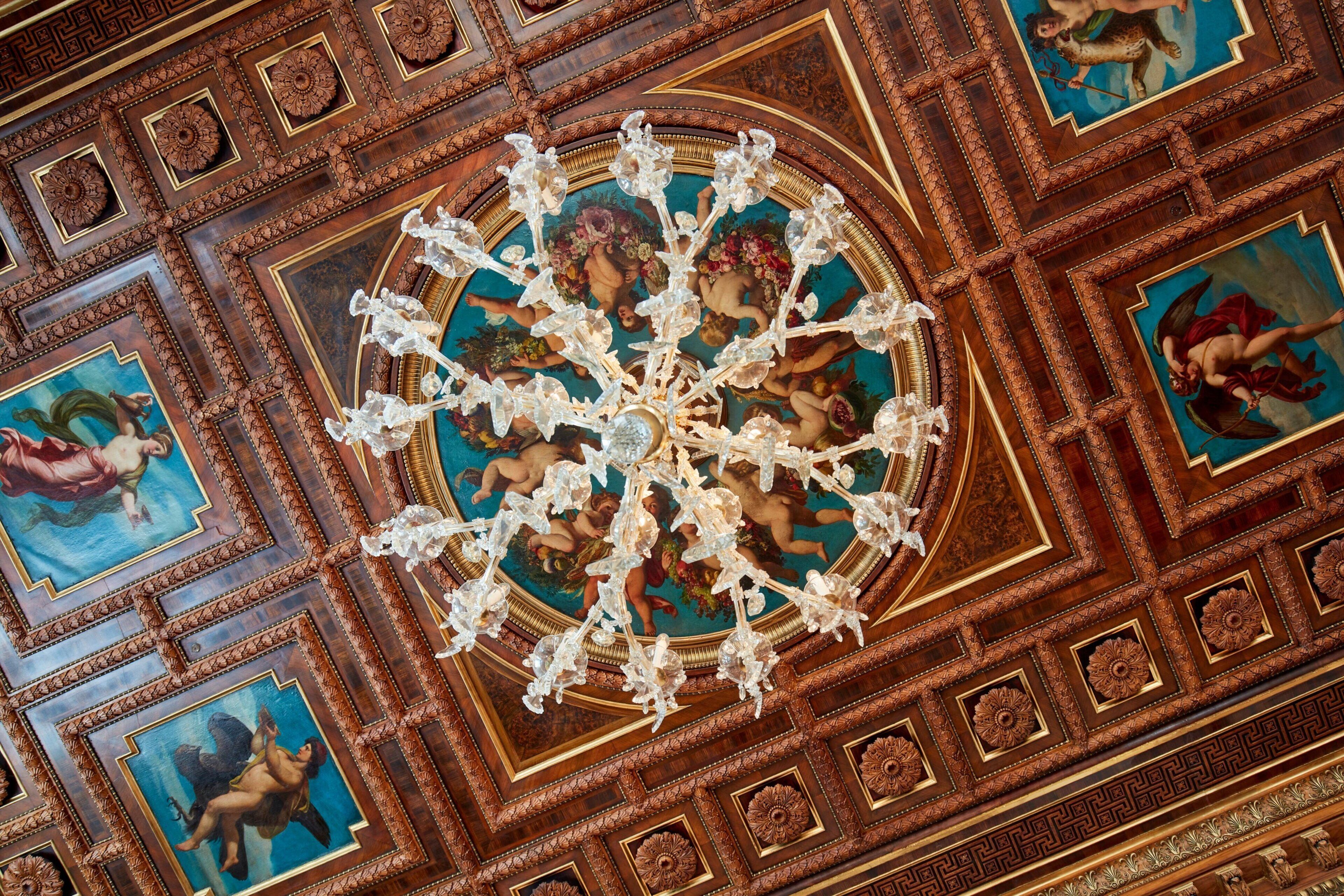 A ceiling with intricate woodwork and a central chandelier.