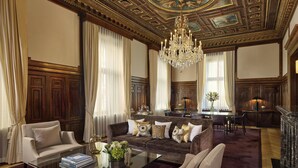 A luxurious living room with a grand chandelier, a plush sofa, and a glass coffee table. - The Ritz-Carlton, Vienna (Vienna)