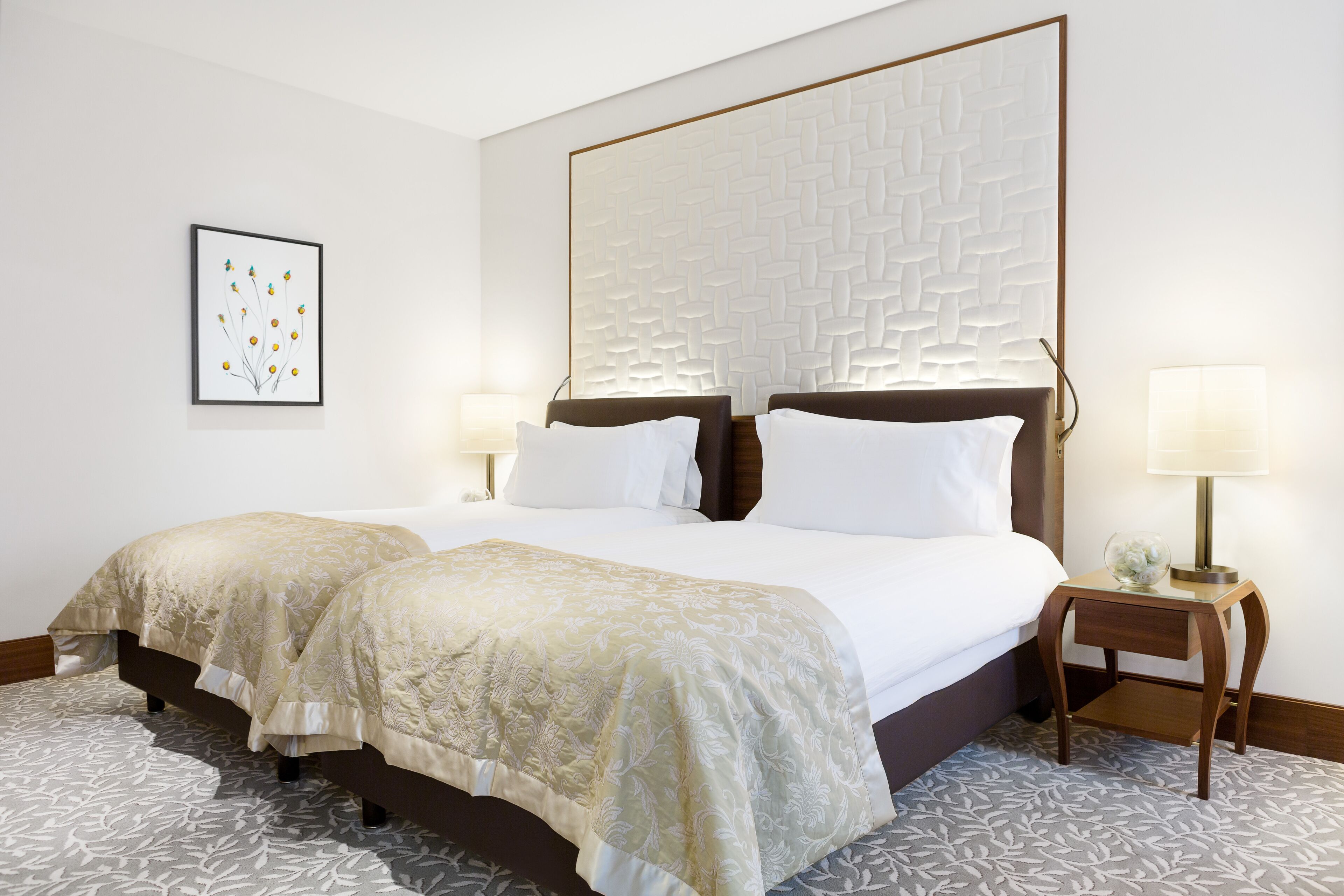 A double bed with a headboard, two bedside tables, and a framed artwork on the wall.