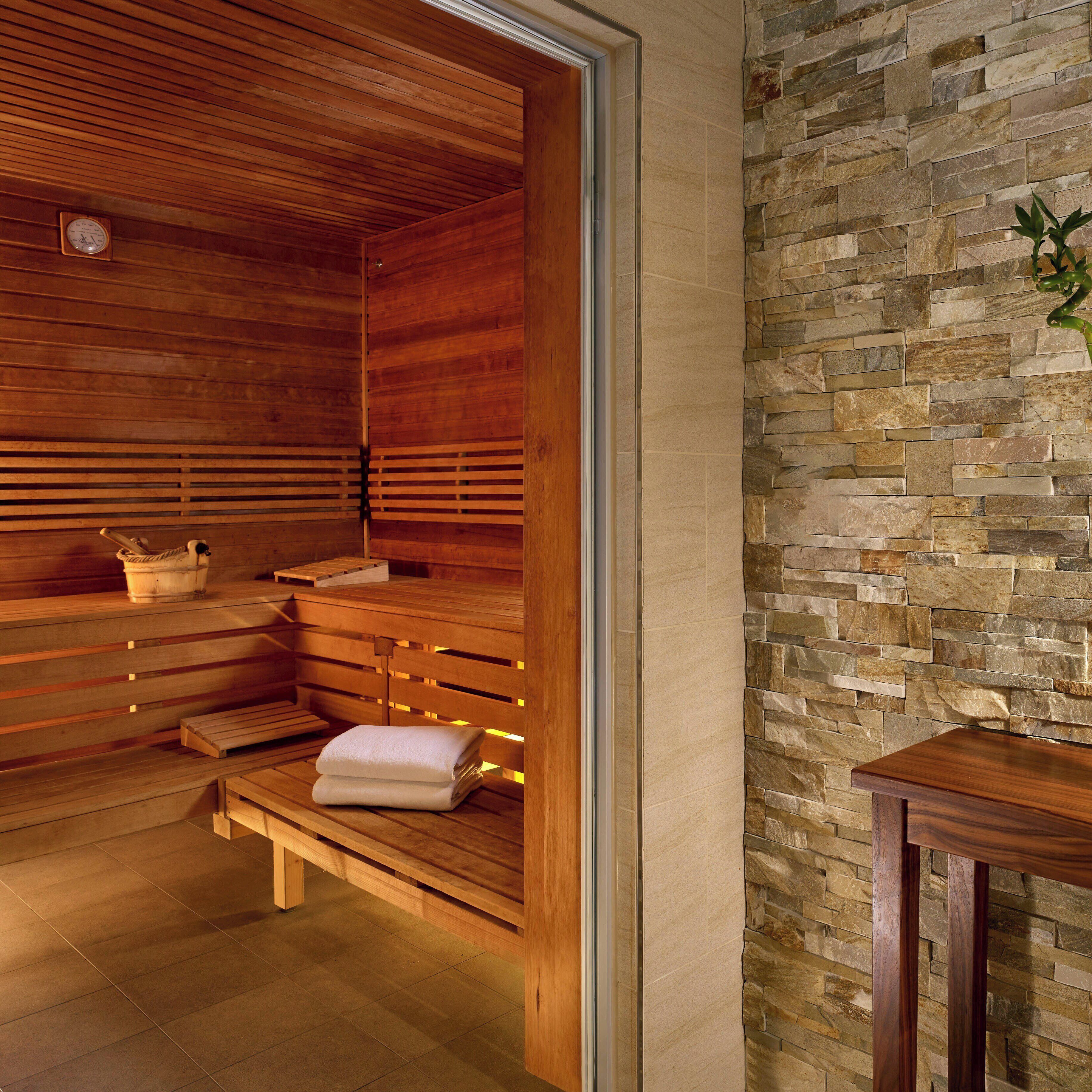A sauna with wooden benches and a stone wall.