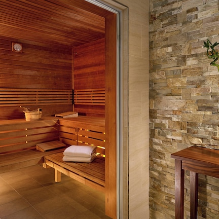 A sauna with wooden benches and a stone wall.