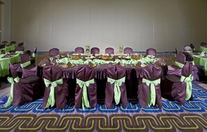 A banquet hall with round tables set for a formal event, each with green tablecloths, purple chairs, and centerpieces. - Hilton Garden Inn Texarkana (Texarkana)