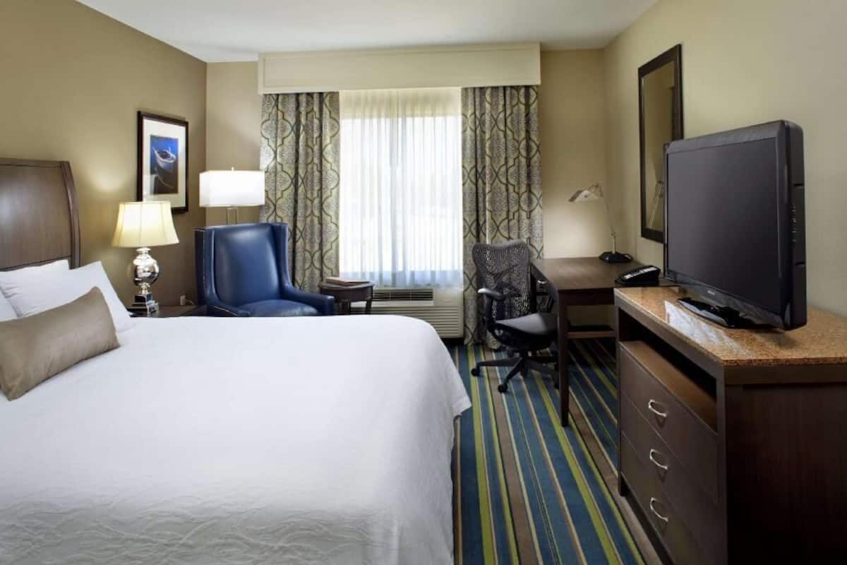 A hotel room with a bed, a desk, a television, and a chair.