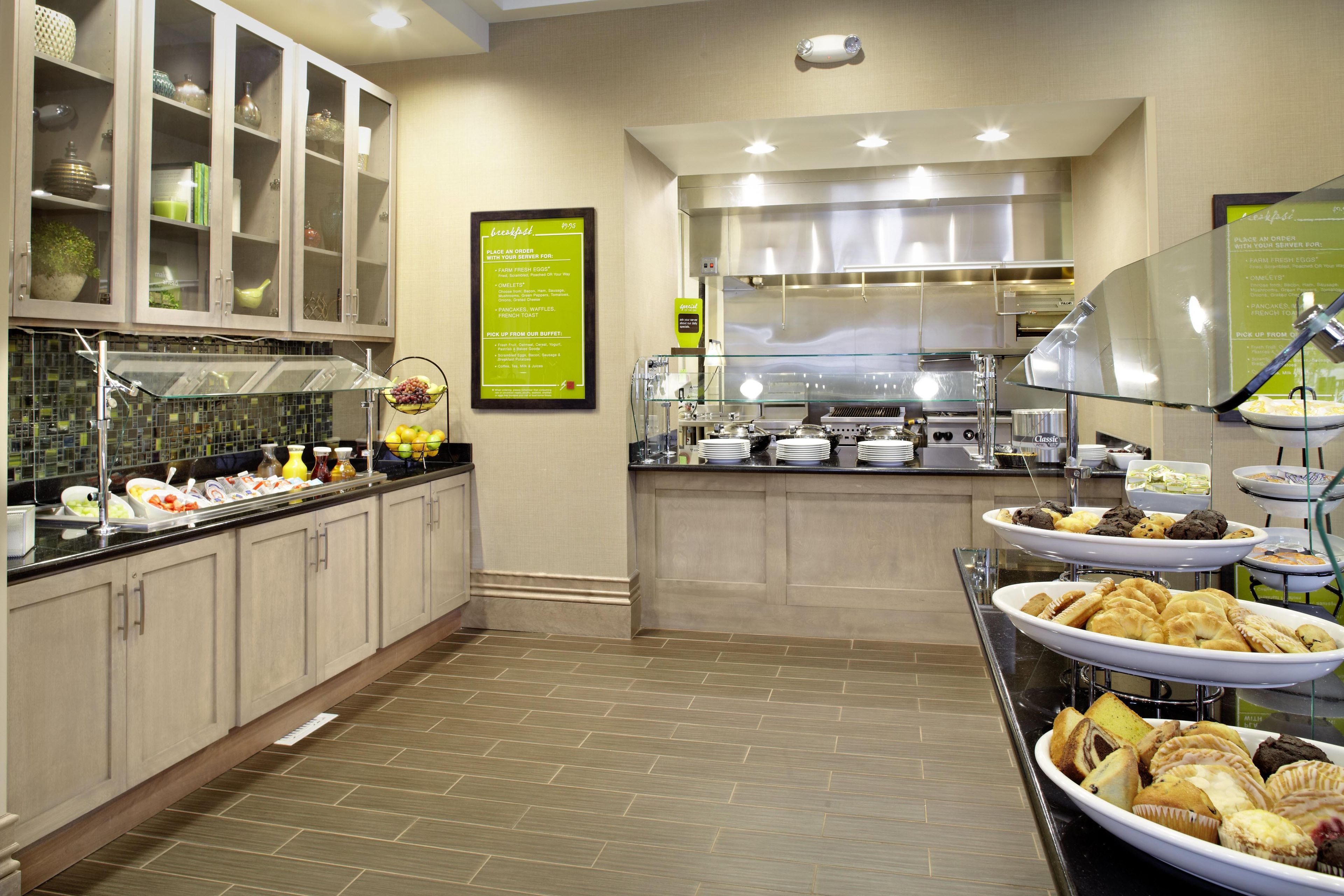 Een buffetgedeelte met diverse food stations, waaronder een schaal fruit en een keuze aan gebak.